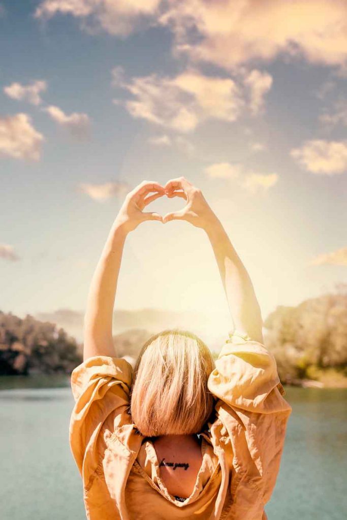 Mujer haciendo un corazón frente al sol